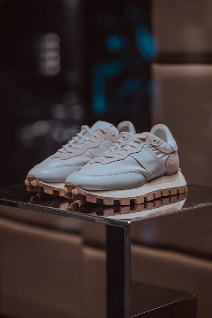 about-img-01 Elegant white sneakers displayed on a reflective surface, perfect for fashion-forward looks.