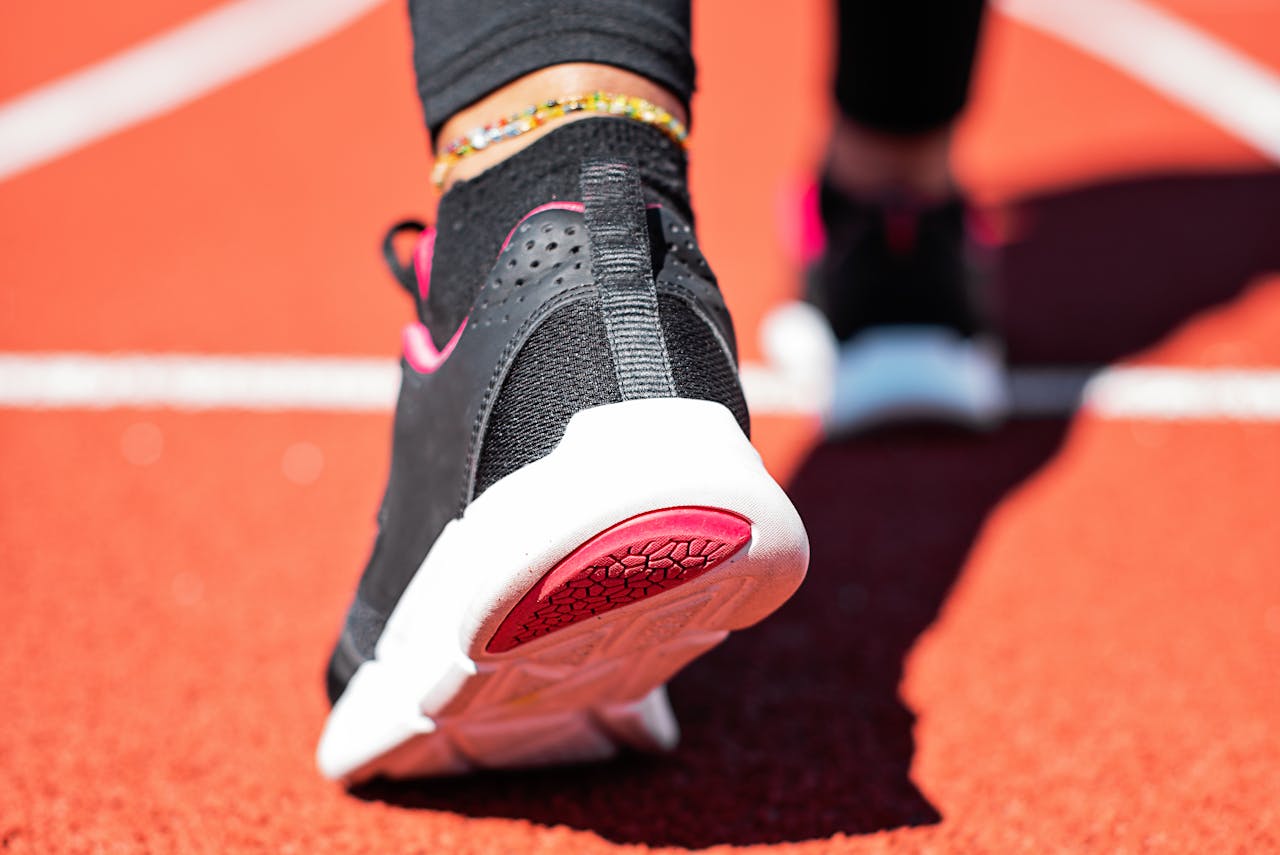 home-img Close-up of a runner's foot with athletic sneaker on a vibrant track surface.